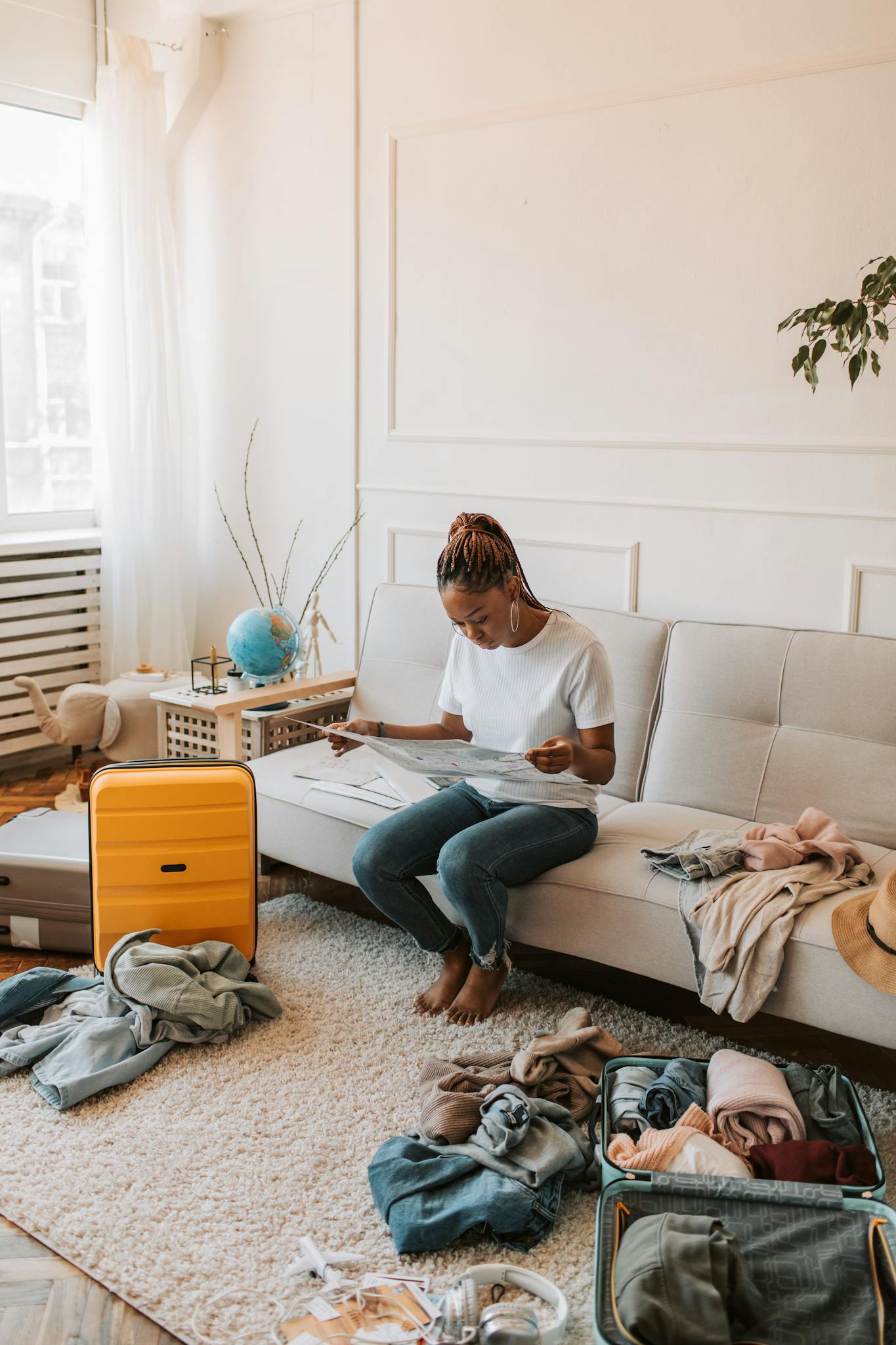 A woman packs her suitcase in a cozy living room, surrounded by clothes and travel essentials.