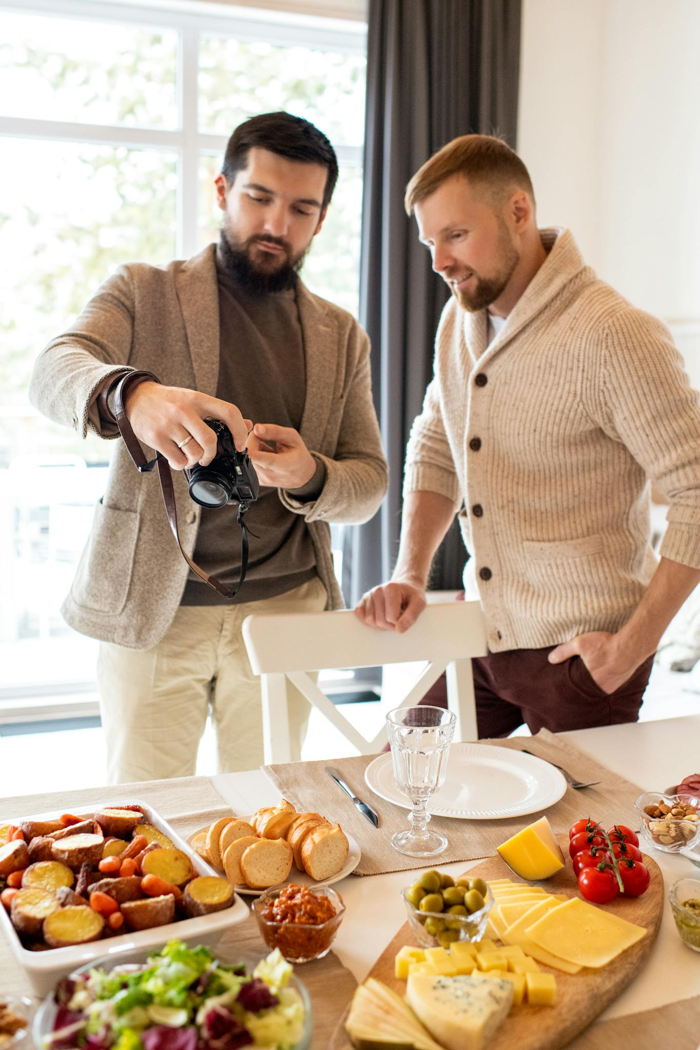 Two men enjoying a casual breakfast with a variety of foods in a cozy indoor setting.