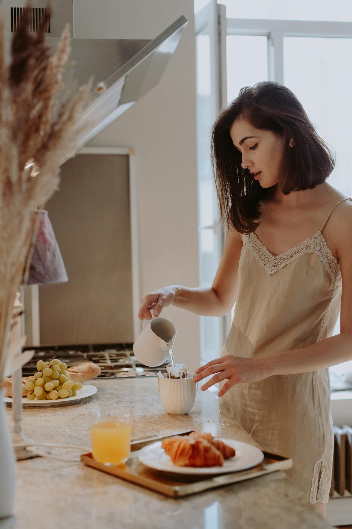 Young woman preparing breakfast in a stylish kitchen, adding milk to her coffee.